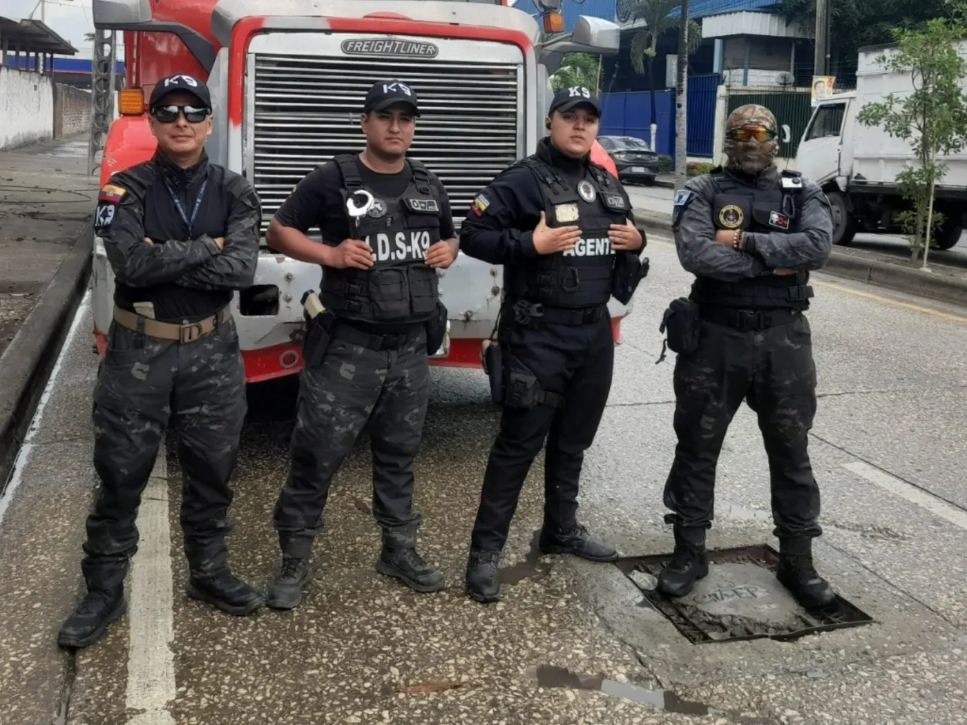 Equipo de guías de Intervención Canina con uniforme táctico frente a un tráiler