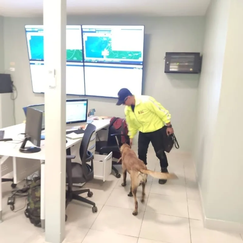 Guía K9 con su perro en una sala de monitoreo con pantallas